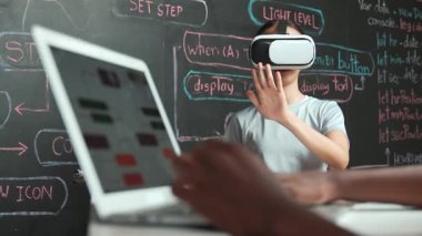 Kara tahtadaki Afrikalı öğrenci el kodlaması ya da programlama sisteminin web geliştirme planıyla kapatılması. Bu arada genç bir kız da mühendislik dersiyle kara tahtada oynuyor. Yenilik. Öğretim