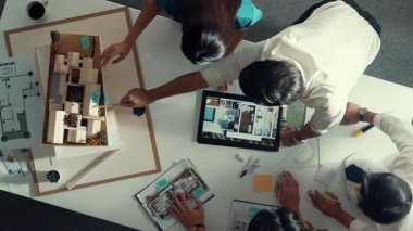 Mimar mühendis ekibinin tartıştığı ve tablet görüntüleme inşaatını planlı ve ev modeliyle toplantı masasında işaret ettiği en tepeden aşağı bakış açısı. Çeşitli tasarımcı tasarım evleri. Hizalama.