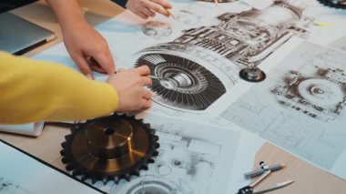 İki mühendis, mekanik bileşenleri ve teknik çizimleri ortak çalışma alanında tartışıyor ve analiz ediyor, tasarım alanında hassasiyet ve yenilik sergiliyor. SACTR