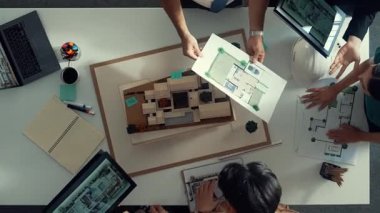 Yöneticinin ev modelini göstermesi ve bina tasarımını açıklaması. Tablet ev planı sergilenirken iç yapı hakkında beyin fırtınası yapan mimar mühendisinin hava görüntüsü. Hizalama.