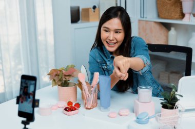 Genç, güzel Asyalı kozmetik makyaj ruju matte pastel rengini modern odadaki sosyal medyada kol testi tanıtımında en çok satanlar listesinde gösteriyor. Taktik.