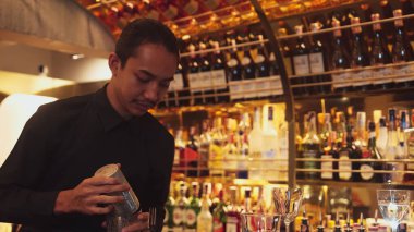 Gülümseyen Asyalı akıllı barmen iki eli karışık kokteylde titreyerek lüks tezgah barında hazırlanıyor, özel içecek hazırlıyor gece hayatı içkisi gece kulübü sıcak. Vinosity.