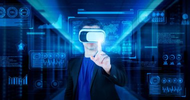 Finansal verileri analiz ederken veri merkezinde duran kulaklıklı bir iş adamı. Yönetici, pazarlama istatistiksel hologramını işaret ediyor ve karar verirken artırılmış gerçeklik gözlükleri kullanıyor. Yaratıcılık.