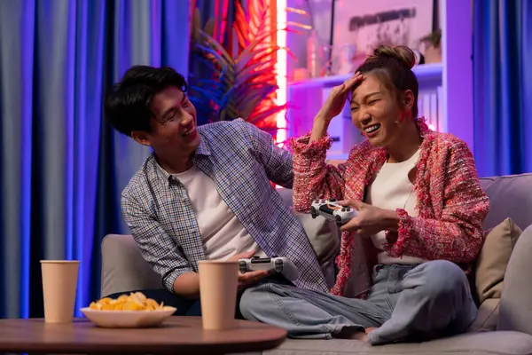 Oyun oynayan mutlu çiftin oturduğu kanepe joystickle oyun oynuyordu. Önden atıştırmalıklar ve kazanmak için gözlerini kapayan içkiler, evdeki modern neon ışıklı oturma odasında eğlenceli bir şekilde meydan okumaydı. İnfobahn.