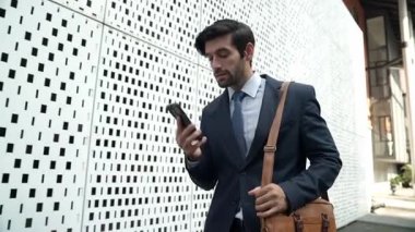 İş adamı telefona cevap verir ve iş yatırımları hakkında konuşur. İş planı, pazarlama stratejisi ya da çalışma hakkında konuşmak için akıllı telefonla konuşurken sokakta yürüyen mutlu bir yönetici. Sevinçli..