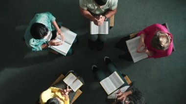 Yetenekli çeşitli duaların el ele tutuşması ve daireler çizerek Tanrı 'ya dua edişinin üst görüntüsü. Kucaklarda açık incille otururken el ele tutuşan insanların yukarıdan aşağı hava görüntüsü. Sempozyum.