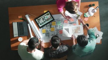 Yöneticinin planlara bakarken birlikte çalışmasını yukarıdan aşağıya izlemek. Mimar mühendis ekibinin fikir ya da planlarını paylaşırken dizüstü bilgisayar ve planlarla toplantı masasında durması. Sempozyum.