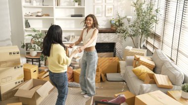 Taşınırken oturma odasında mutlu lezbiyen aşıklar dans ediyor. Birkaç arkadaş müzik eşliğinde salonda karton kutularla dans ederek serbest dans ediyorlar. Yeniden yerleştirme. Myrmidon.