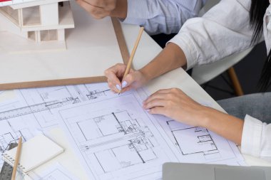 Profesyonel erkek mühendis ev modelini cetvel kullanarak ölçerken güzel bir iş arkadaşı da plan üzerinde yazarak birlikte çalışıyor. Yaratıcı tasarım ve takım çalışması. - Yakın çekim. Tertemiz..