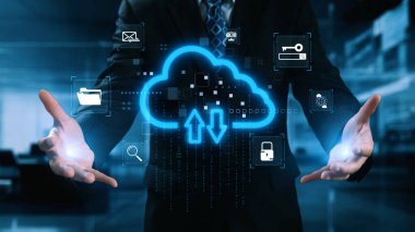 Bir işadamı dijital bulut teknolojisi konseptini yükleme ve indirme sembolleriyle sergiliyor. Çeşitli simgeler modern bir çalışma alanında veri güvenliğini ve bağlantıyı göstermektedir. Dörtgen