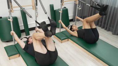Bir grup müşteri, çekirdek dayanıklılığını ve bacak bağını geliştirmek için Cadillac reformatör makinesinde pilates egzersizleri yapıyor. Sağlıklı müşterilerin daha düşük poz verip kaldırma pozlarının üst görüntüsü. Sağlıklılık. Alışkanlık.