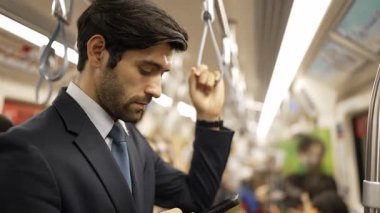 Profesyonel bir iş adamı trende etrafını insanlar sarmışken saate ve telefona bakıyor. Yönetici e-posta kontrolü, bulanık geçmişi olan pazarlama stratejisi planlama. Sevinçli..