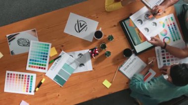 Proje yöneticisi renk paletleri seçerken tasarımcının tablete baktığı yukarıdan aşağıya hava görüntüsü. Profesyonel grafik tasarımının en üst görüntüsü ve logoya bakın. Yetenekli ekip grafikleri seçiyor. Sempozyum.