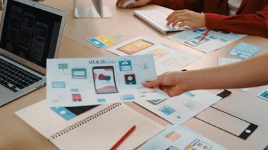 Mobil uygulama için kullanıcı arayüzü prototipini ofis çalışanlarına sunan harika bir şirket çalışanı. UX UI tasarımcısı kağıt üzerinde simge tasarımının işlevini açıklıyor. Sinerjik