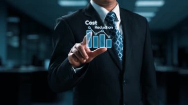 Takım elbiseli bir işadamı modern bir ofiste duruyor, canlı finansal simgelerle çevrili bir maliyet azaltma grafiği sunuyor, başarıyı ve stratejik büyümeyi simgeliyor. Dörtgen