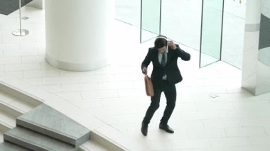 İş adamı kapıda dans ederken kulaklıkla şarkı dinler. Yöneticinin başarılı bir projeyi kutlamak için müziğe yönelmesi ya da terfi alma ve satışları artırma konusunda iyi haberler. Sevinçli..
