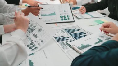 Çeşitli bir ekip, modern bir ofisteki çizelge ve verileri analiz ederek ortak bir toplantıya katılıyor. Atmosfer üretkenliği destekliyor ve ticari başarı için fikirlerimizi paylaşıyoruz. SACTR