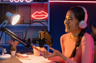 Geceleri podcast 'te olumlu konuşmalar yapan, pembe neon ışıklı modern stüdyoda sunum için dizüstü bilgisayar kullanan, gülümseyen, genç, güzel Asyalı bir etkileyiciydi. Taktik.