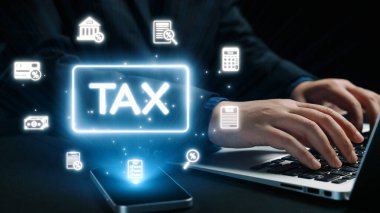 Dijital vergi simgeleriyle çevrili bir dizüstü bilgisayara, modern mali yönetimi ve günlük hayattaki verimli vergi hazırlığının önemini simgeleyen bir kişi yazı yazar. Dörtgen