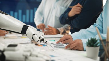 Bir robot el, iş görüşmesi sırasında insan meslektaşlarıyla iletişim kurar. Çeşitli çizelge ve grafikleri analiz ederler, modern ofis ortamında işbirliği gösterirler. Noogenesis