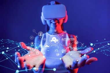 Bir insan sanal gerçeklik teknolojisiyle etkileşime girer, otomasyon kavramlarını ve dijital arayüzleri sergiler, modern endüstri ortamındaki yenilikleri sembolize eder. XDMCP