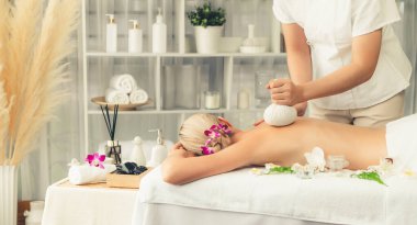 Sıcak bitkisel top spa masaj vücut tedavisi, masör kadın vücuduna nazikçe şifalı bitki torbası bastırıyor. Aromaterapi dinlenme sükuneti ve sükuneti kaplıca salonundaki atmosferi aydınlatıyor. Sessiz.