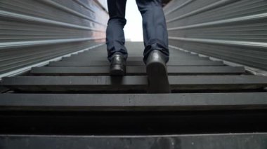 Merdivenlerden çıkan başarılı iş adamının bacağına yakın plan. Müdürün iş yerini değiştirmesi, yeni bir şey keşfetmesi, gelişmesi, terfi etmesi ya da gün ışığına çıkması. Yükseliyor. Bacağa odaklan. Sevinçli..