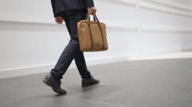 Profesyonel iş adamının bacağını tutarken yakın plan fotoğrafı. Proje yöneticisinin bacağa odaklanmış görüntüsü. Seyahat, taşınma, yolculuk, yürüyüş, yeni bir pozisyon alma, iş değiştirme. Sevinçli..