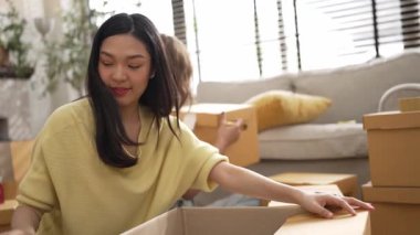 Çekici bir oda arkadaşı oturma odasında paket paketlerken pakette konum yazıyor. Mutlu satıcı birlikte çalışıyor ve teslimat paketini hazırlıyor. Girişimci kargo kutusu paketliyor. Myrmidon.