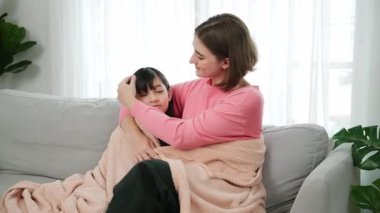 Kafkasyalı anne enerjik kızını sıcak bir battaniyeyle örtüyor. Mutlu anne evinde kanepede otururken akıllı öğrencisini battaniyeye sardı. Sevgi ve şefkat göstergesi. Pedagoji.