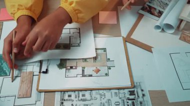 İç tasarımın yaratıcı sürecinde yer alan, kumaş ve planlama malzemeleriyle çevrili renk örnekleri ve tasarımları keşfeden ellerin yakın görüntüsü. SACTR