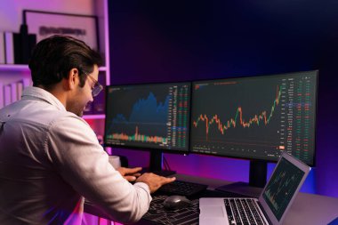 Akıllı tüccar işadamı, karanlık oda gecesinde neon ışıklı ofisteki arama pazarında yüksek kârla ekranda bilgisayar ve bilgisayar üzerinde dinamik borsa yatırımları üzerinde yoğunlaşıyor. Tahmin et..