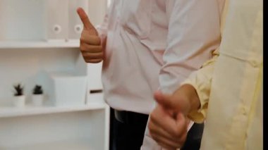 Panoramik video mutlu Asyalı şirket çalışanı renkli günlük kıyafet giyer yan yana durur yaratıcı takım çalışmasını, iş istihdamını, HR ajansını sembolize eden başparmağını kaldırır. Sinerjik