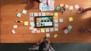 Web tasarımı için birlikte çalışan iş adamlarının üst düzey görüşü. Tasarımcı beyin fırtınası yapan ve web sitesi arayüzü hakkında tartışan ve dijital tasarım ile tablete bakan hava görüşü. Sempozyum.