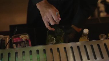 Yakın plan el yapımı barmen. Midori ekşisini limon şurubuyla karıştırıp cam hazırlıyor. Gece kulübünde gece hayatı karışımı sergilenen taze yeşil içeceğe odaklanıyorum. Vinosity.