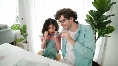 Komik beyaz bir baba ve Amerikalı bir çocuk dudak ve burun arasına kalem koyarken komik bir yüz ifadesi takınıyorlar. Birlikte mühendislik komut yazma ve masadaki dizüstü bilgisayarda yapay zeka üretme üzerine sevimli bir aile çalışması. Pedagoji.