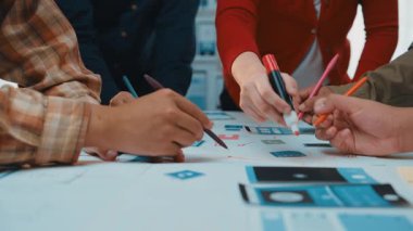 Değişik profesyonellerin birlikte beyin fırtınası ve proje planlaması yaptığı dinamik bir iş yeri sahnesi. Eller aktif olarak yazmaya ve fikirleri tartışmaya odaklan. SACTR