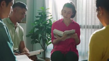 Katlanmış eller yaparken kucağında haçla İncil okuyan duaların üst görüntüsü. İnanç, güven ve umutla Tanrı 'ya dua eden farklı insanların havadan görünüşü. Ve daireler çizerek oturuyor. Sempozyum.