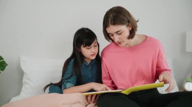 Beyaz bir anne, tatlı kızının dinlediği hikayeleri okuyor. Asyalı kız yatmadan önce hikâyeyi anlatırken işaret etti. Birlikte vakit geçirirken mutlu bir aile yatakta oturuyor. Pedagoji.