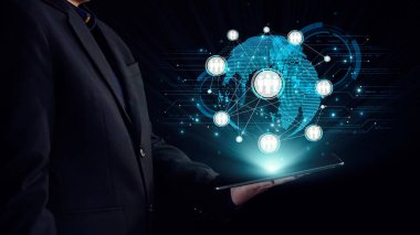 Küresel iletişimi ve teknolojideki modern etkileşimleri gösteren dijital dünya haritası ile çevrili bir tablet kullanan bir işadamı. Dörtgen