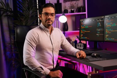 Bilgisayar ekranındaki yazılım geliştirme kodlamasına karşı poz vermek için akıllı bilişim geliştirici görünümlü kamera profilleri, neon ışıklı siber oda ofisinde program güncellemesi internet sitesi verileri sunuyor. Tahmin et..