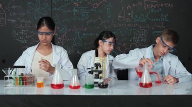 Mesleki çeşitlilik gösteren öğrenci, STEM fen dersinde, kimyasal teoriyle karatahta deneyimi yaşıyor. Genç bir delikanlı biyo-kimyasal çözeltiyi mikroskop ile masada karıştırıyor. Öğretim