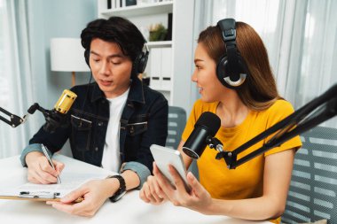 Gülümseyen radyo etkili sunucular, kulaklık takıp sosyal medyayı canlı yayında dinleyicilere telefon ve dizüstü bilgisayarla canlı yayınlıyorlar. İnfobahn.