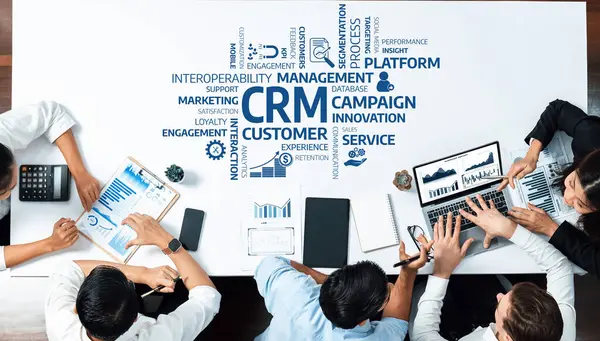 Müşteri ilişkileri yönetimi üzerinde yoğunlaşan dinamik bir iş toplantısı masa etrafında gerçekleşirken, takım üyeleri dijital cihazlar ve çizelgeler kullanarak tartışmalara giriştiler. Dostluk