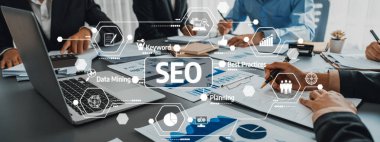 Modern bir ofis ortamında grafikler ve veri analizleri üzerinde işbirliği yapan profesyonellerin yer aldığı dinamik bir iş toplantısında SEO stratejileri ele alındı. Dostluk