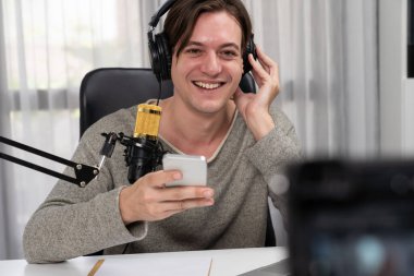 Akıllı yayıncının sunucu kanalı canlı sosyal medya yayını ile akıllı telefon kullanarak dinleyiciyle sohbet ediyor, kulaklık takarak modern ev stüdyosunda video kaydediyor. Bireysel.