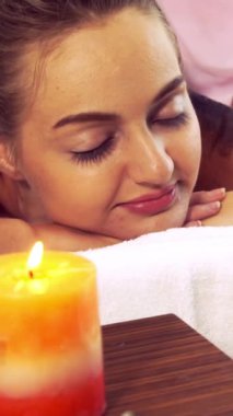 Rahatlamış genç bir kadın masaj için spa yatağında uzanıyor. Lüks bir spa merkezinde masaj terapistinin geleneksel otlarını ve baharatlarını kullanıyor. Sağlık, stres atma ve gençleştirme kavramı.