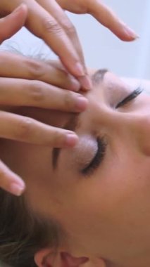 Lüks bir spa merkezinde masaj terapisti tarafından yüz masajı ve spa tedavisi için kaplıcaya uzanmış rahat bir kadın. Sağlık, stres atma ve gençleştirme kavramı.