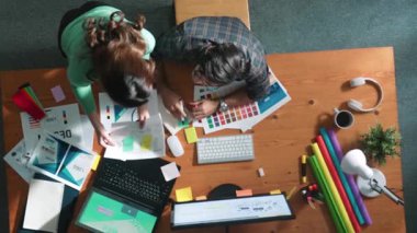 Tasarımcı yazma fikri ekrana bakarken proje yöneticisinin üst görünümü. Akıllı iş adamlarını kapat ve tasarımcı palete bakarken logo tasarımı fikrini açıkla. Sempozyum.