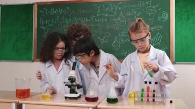 Kafkasyalı öğrenci kimyasal çözüm hazırlarken, yetenekli çocuklar mikroskop altında bakıyorlar. Profesyonel öğretmen, tahtada otururken deney yapıyor. Pedagoji.